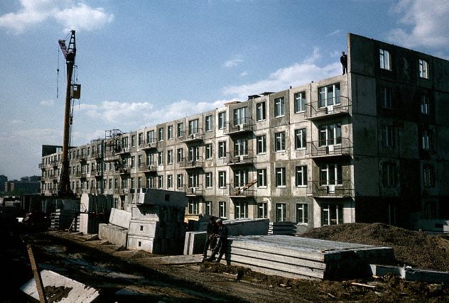 1964 год. Строительство хрущёвки. На заметку: cтроительство «хрущёвок» продолжалось с 1959 по 1985 год. В Ленинграде строительство хрущёвок было прекращено в 1970-х годах. Первые проекты «хрущёвок» были с черепичными или шиферными крышами, однако уже имели характерную планировку. В рамках кампании по борьбе с архитектурными излишествами, последующие проекты этих зданий имели более дешёвые в исполнении плоские битумные крыши с низким чердачным пространством, обычно засыпанным изоляционным материалом и имеющим лишь вентиляционные отверстия наружу (недоступные для кошек, эти пространства стали местом гнездования диких голубей, воробьёв и т. п.). Под окном кухни кирпичной «хрущёвки», которая имеет минимальные размеры, имеется специфический встроенный шкаф типа чулана для хранения продуктов. Толщина наружной стены в этом шкафу обычно полкирпича, в некоторых вариантах построек в этой стене есть наружное постоянно открытое отверстие. В холодный период года шкаф заменял холодильник.