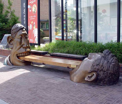 Памятник: мужчины держат зыбами скамейку